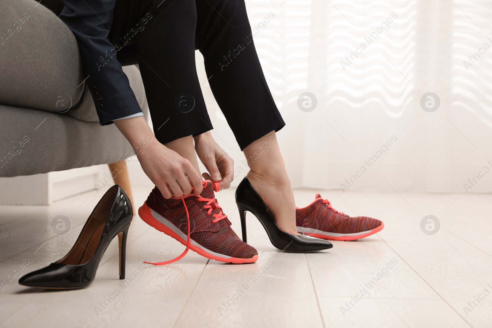 Photo of Woman changing shoes on sofa in office, closeup