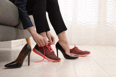 Photo of Woman changing shoes on sofa in office, closeup