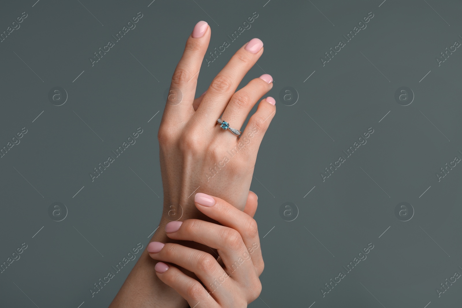 Photo of Woman with elegant ring on dark grey background, closeup