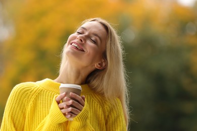Photo of Autumn vibes. Portrait of happy woman with paper cup outdoors. Space for text