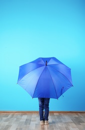 Little boy with blue umbrella near color wall. Space for text