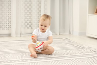 Children toys. Cute little boy playing with spinning top on rug at home