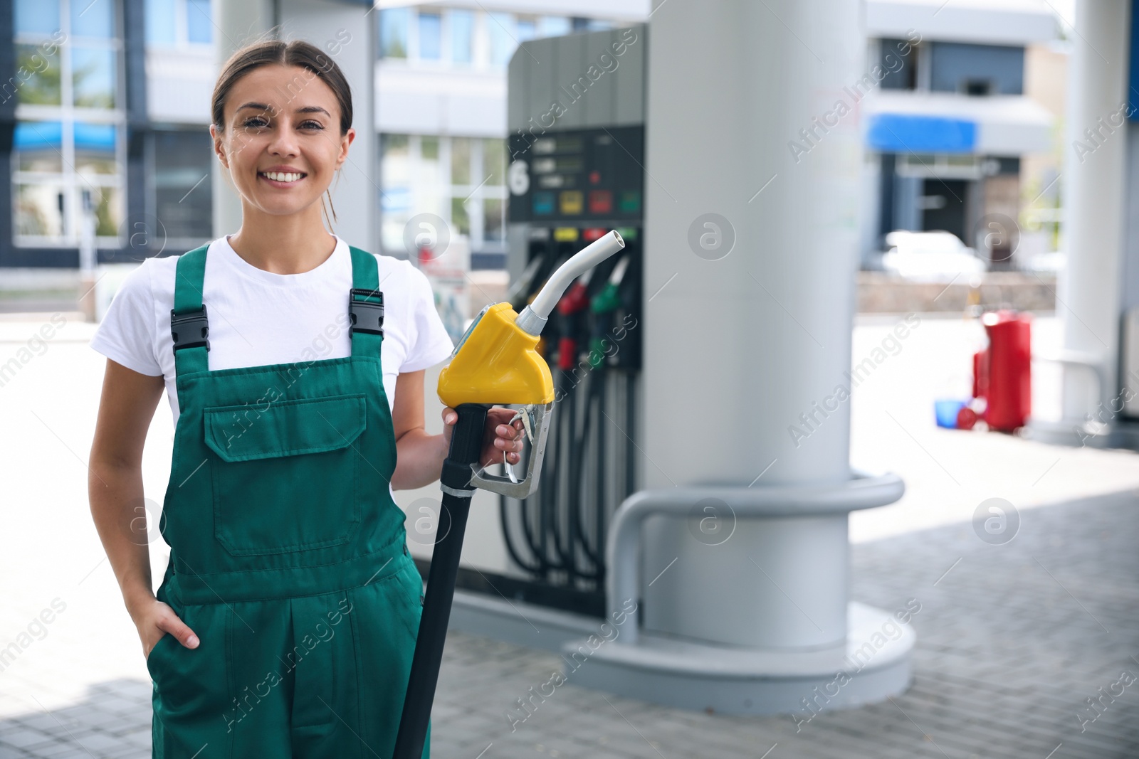 Photo of Young worker with fuel pump nozzle at modern gas station