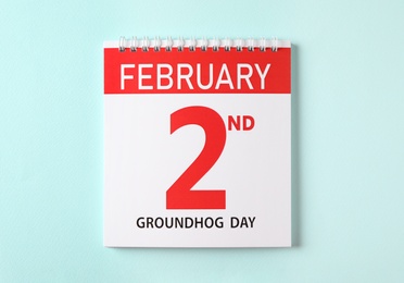 Photo of Top view of calendar with date February 2nd on light blue background. Groundhog day