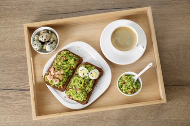 Photo of Slices of bread with tasty guacamole, eggs, shrimp and coffee on wooden table, top view