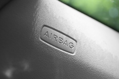 Photo of Safety airbag sign on door in car, closeup