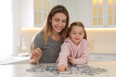 Woman and his little daughter playing with puzzles at home