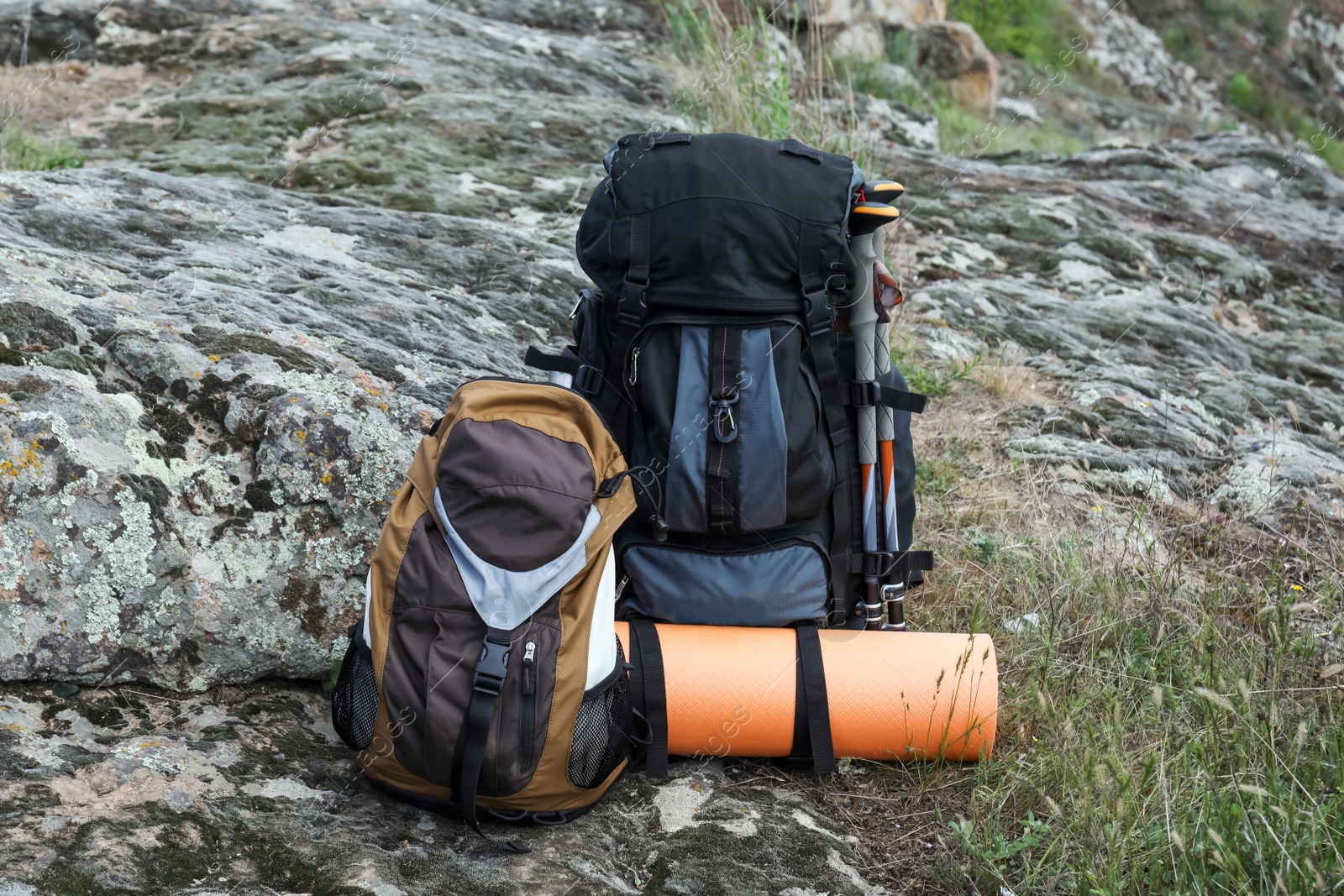 Photo of Backpacks with trekking poles and camping mat on rocky hill