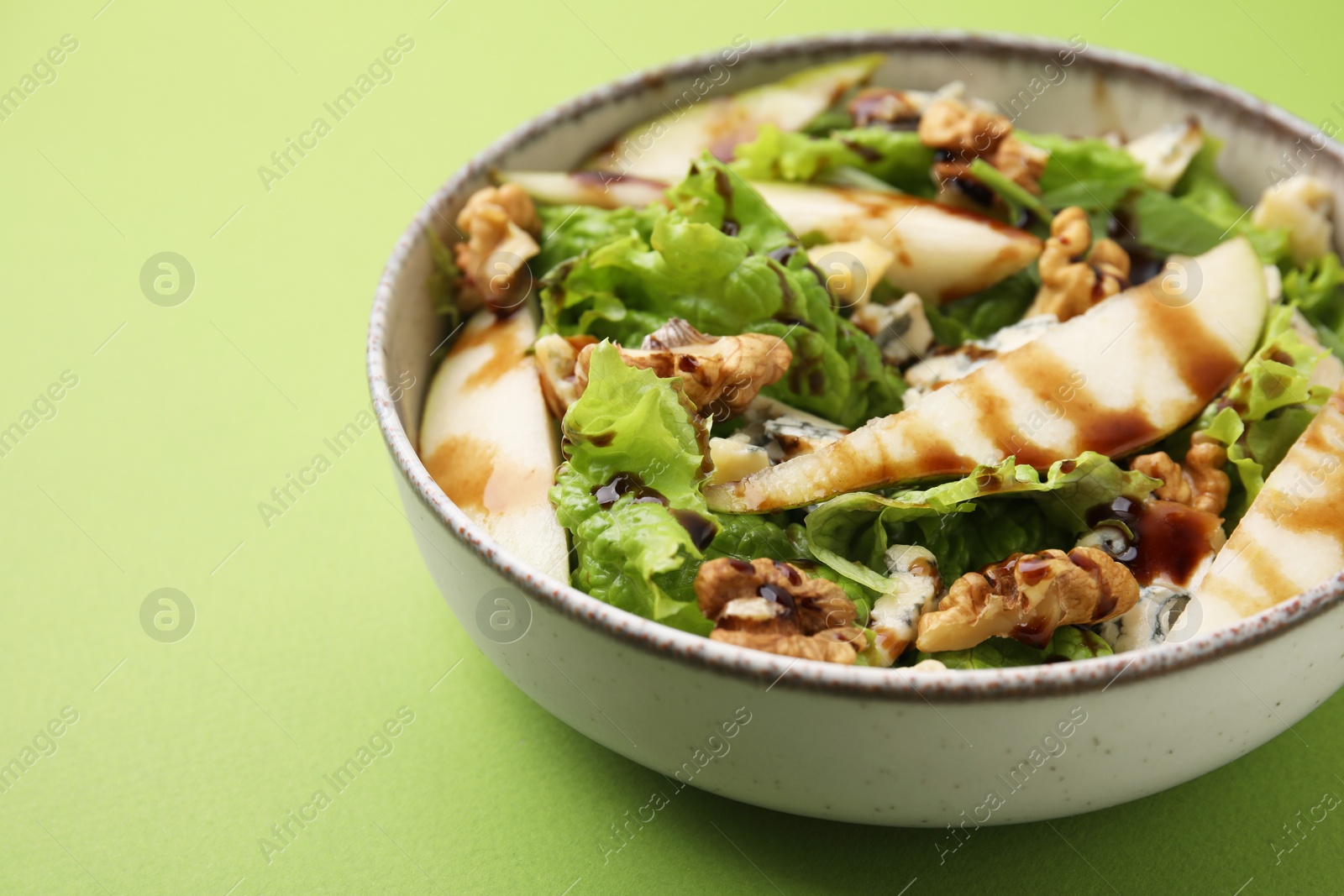 Photo of Delicious pear salad with sauce in bowl on green background, closeup