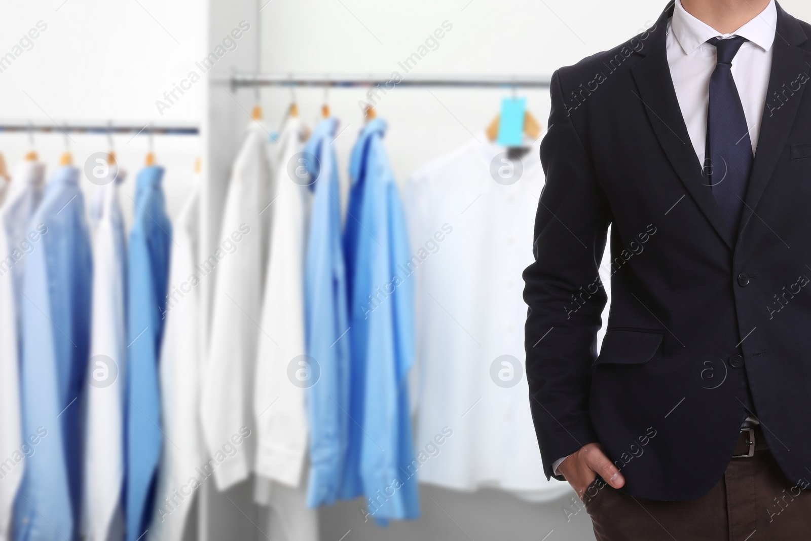 Image of Businessman and rack with clean clothes at dry-cleaner's, closeup. Space for text 