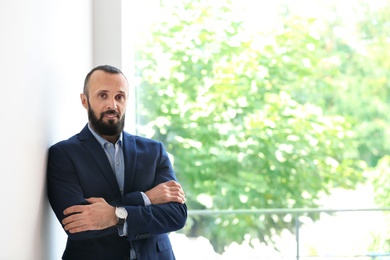 Photo of Portrait of handsome mature man in elegant suit near window