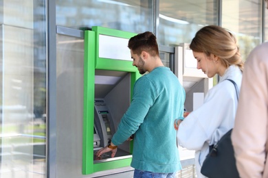 Young people standing in queue to cash machine outdoors