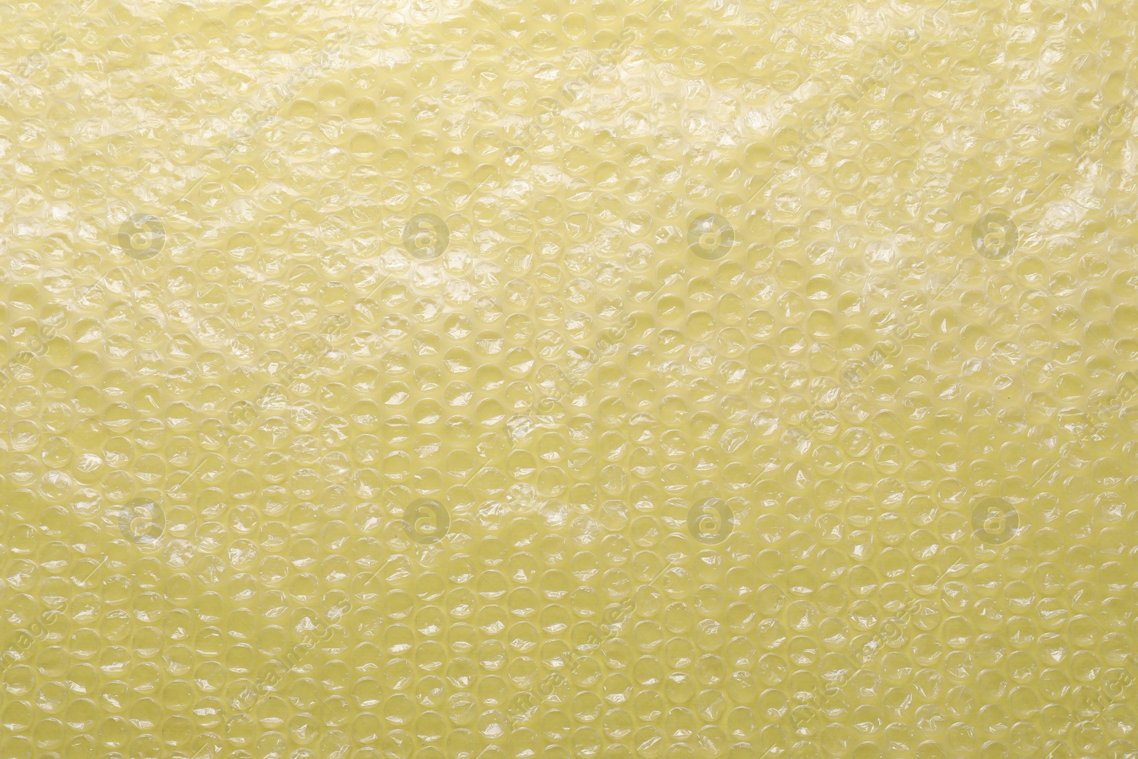 Photo of Transparent bubble wrap on yellow background, top view