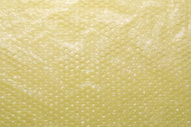 Transparent bubble wrap on yellow background, top view