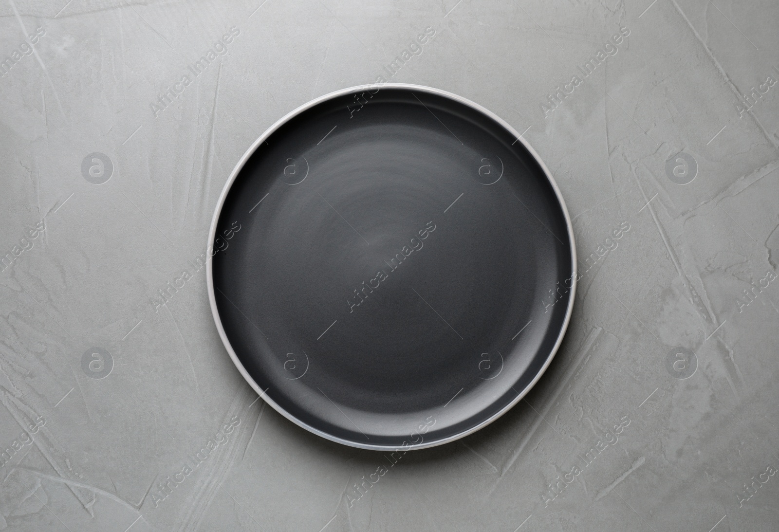 Photo of New dark plate on grey table, top view