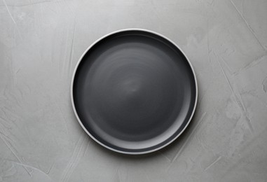 New dark plate on grey table, top view