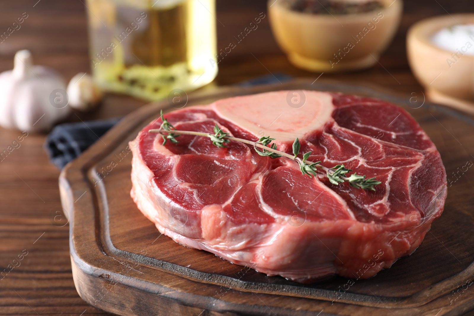 Photo of Piece of raw beef meat and thyme on wooden table, closeup