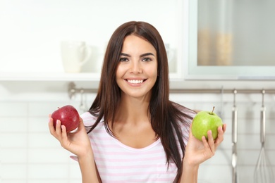 Happy woman holding fresh apples in kitchen