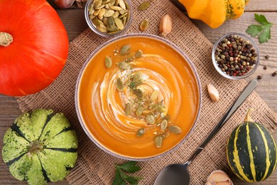 Flat lay composition with bowl of delicious pumpkin soup on wooden table