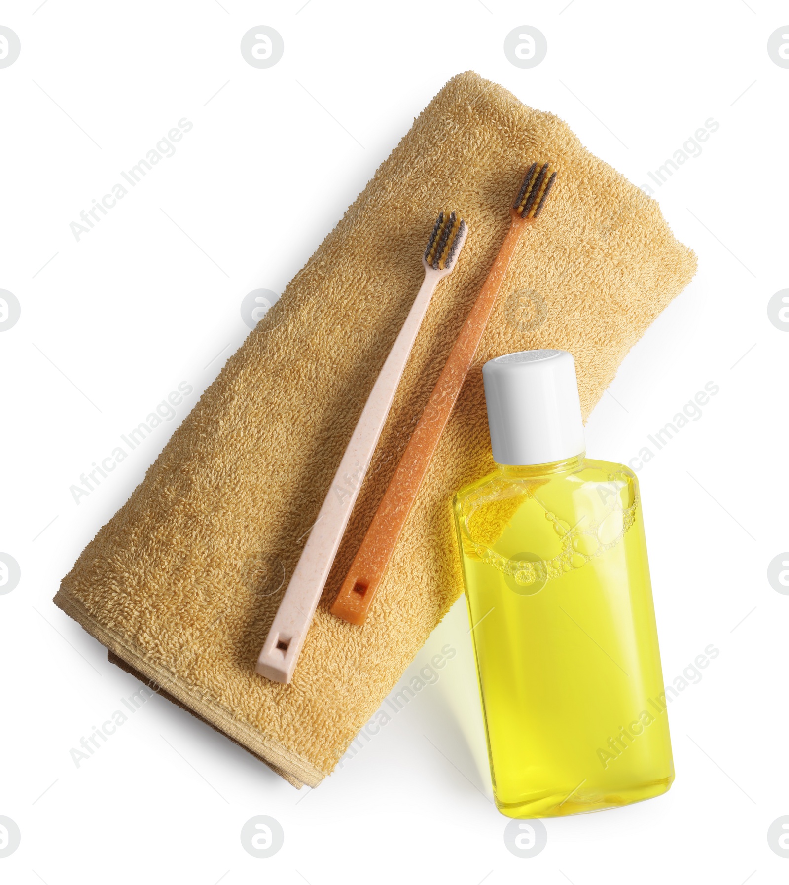 Photo of Fresh mouthwash in bottle, towel and toothbrushes isolated on white, top view