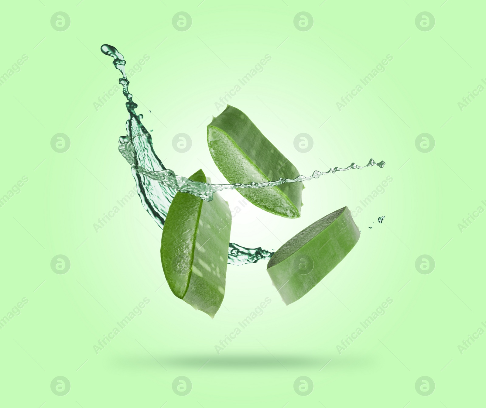 Image of Sliced aloe vera leaf and splash of juice on green background