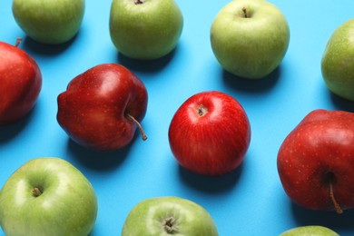 Ripe red and green apples on light blue background, closeup