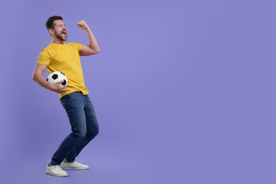 Emotional sports fan with ball celebrating on purple background. Space for text