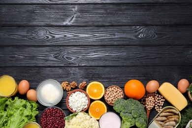 Set of natural food high in calcium on black wooden table, flat lay. Space for text