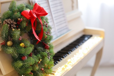 Photo of Decorative wreath on white piano indoors, space for text. Christmas music
