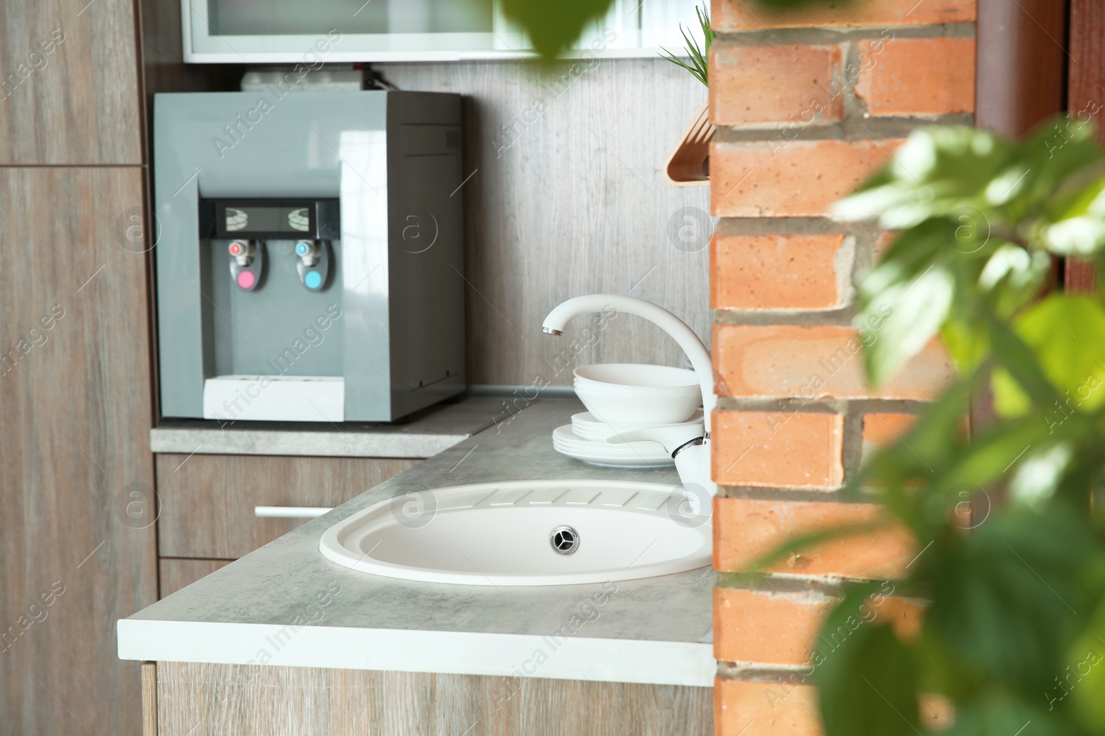 Photo of Kitchen counter with water cooler, sink and clean dishes, indoors