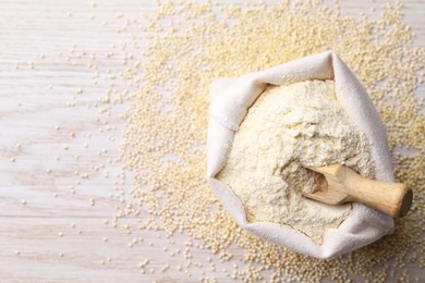 Photo of Sack with quinoa flour, scoop and seeds on white wooden table, top view. Space for text