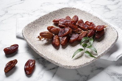 Photo of Tasty sweet dried dates on white marble table