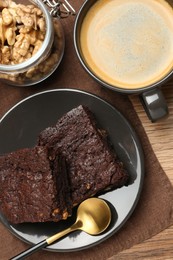 Delicious chocolate brownies with nuts and coffee on wooden table, flat lay