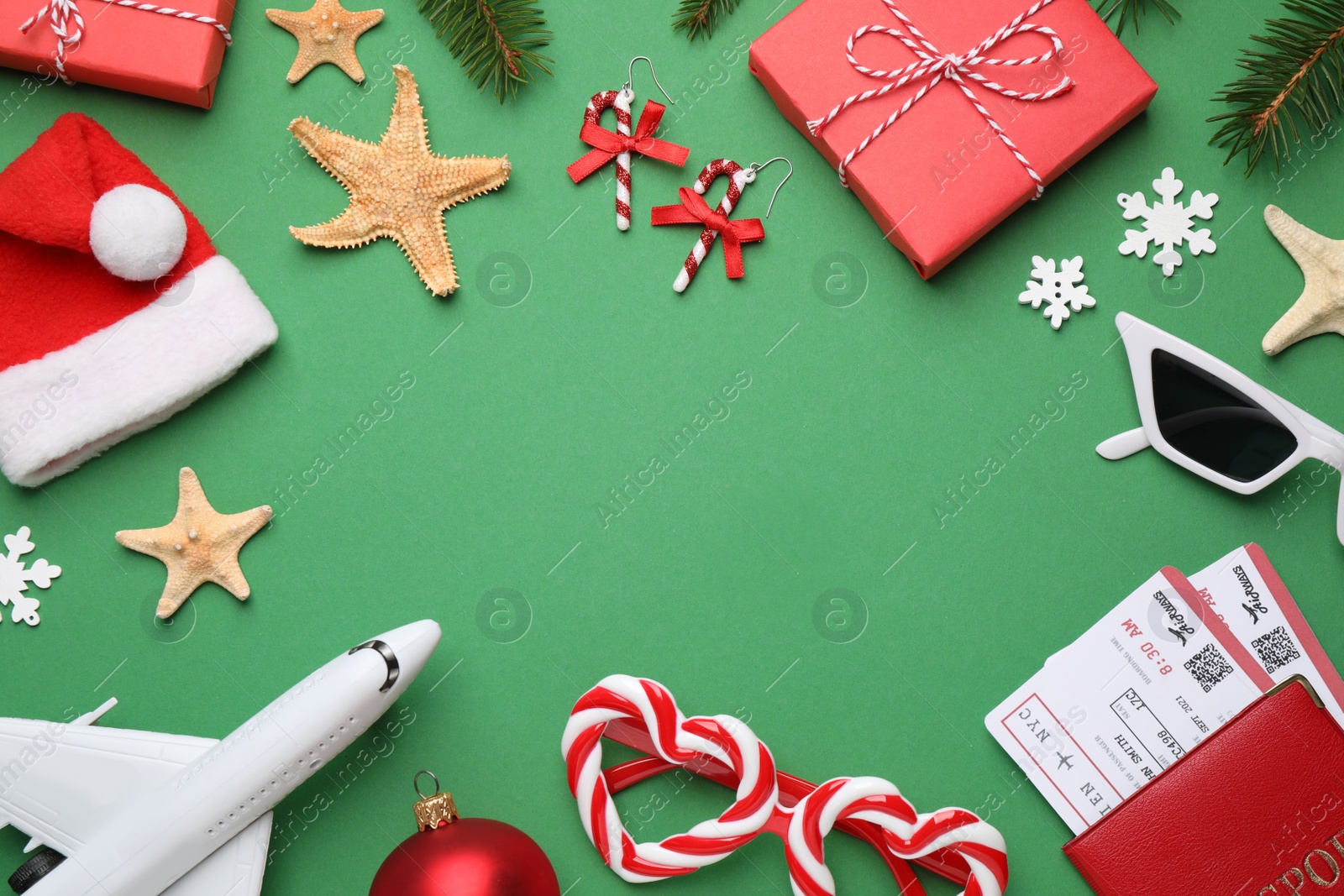 Photo of Frame with toy airplane, festive decor, Santa hat and space for text on green background. Christmas vacation