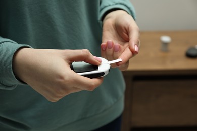 Diabetes. Woman checking blood sugar level with glucometer at home, closeup