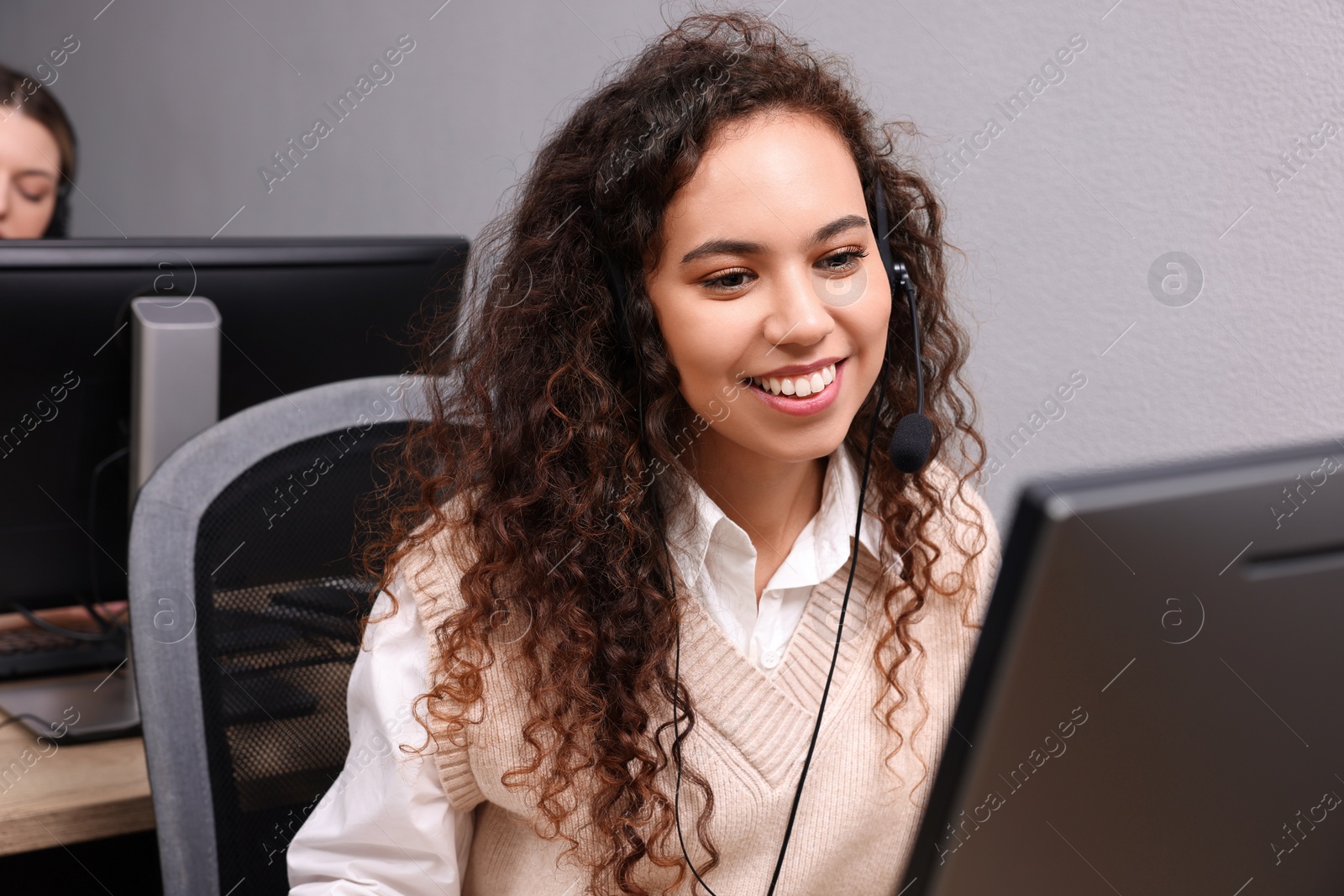 Photo of African American call center operator with headset working in modern office