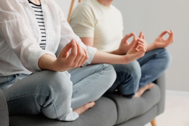 Photo of Couple meditating together on sofa indoors, closeup. Harmony and zen
