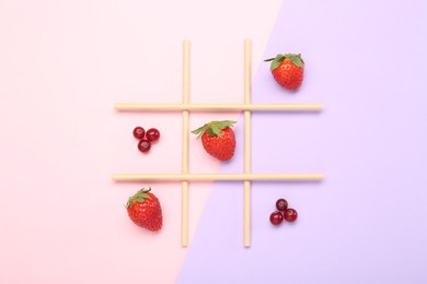Photo of Tic tac toe game made with berries on color background, top view