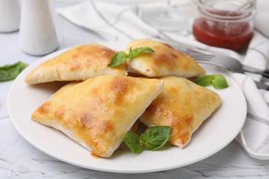 Photo of Delicious samosas and basil on white table, closeup