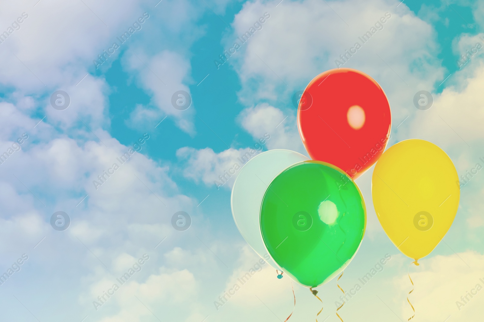 Image of Colorful balloons flying in blue sky with clouds. Space for text