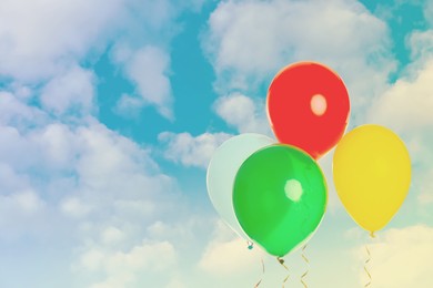 Image of Colorful balloons flying in blue sky with clouds. Space for text