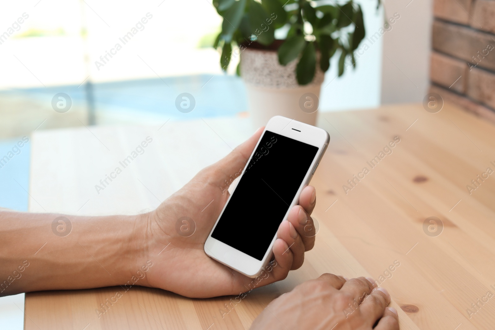 Photo of Man with modern mobile phone at table indoors, closeup