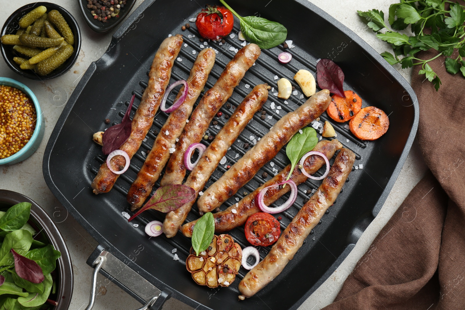 Photo of Grill pan with tasty sausages, spices and vegetables on light table, flat lay