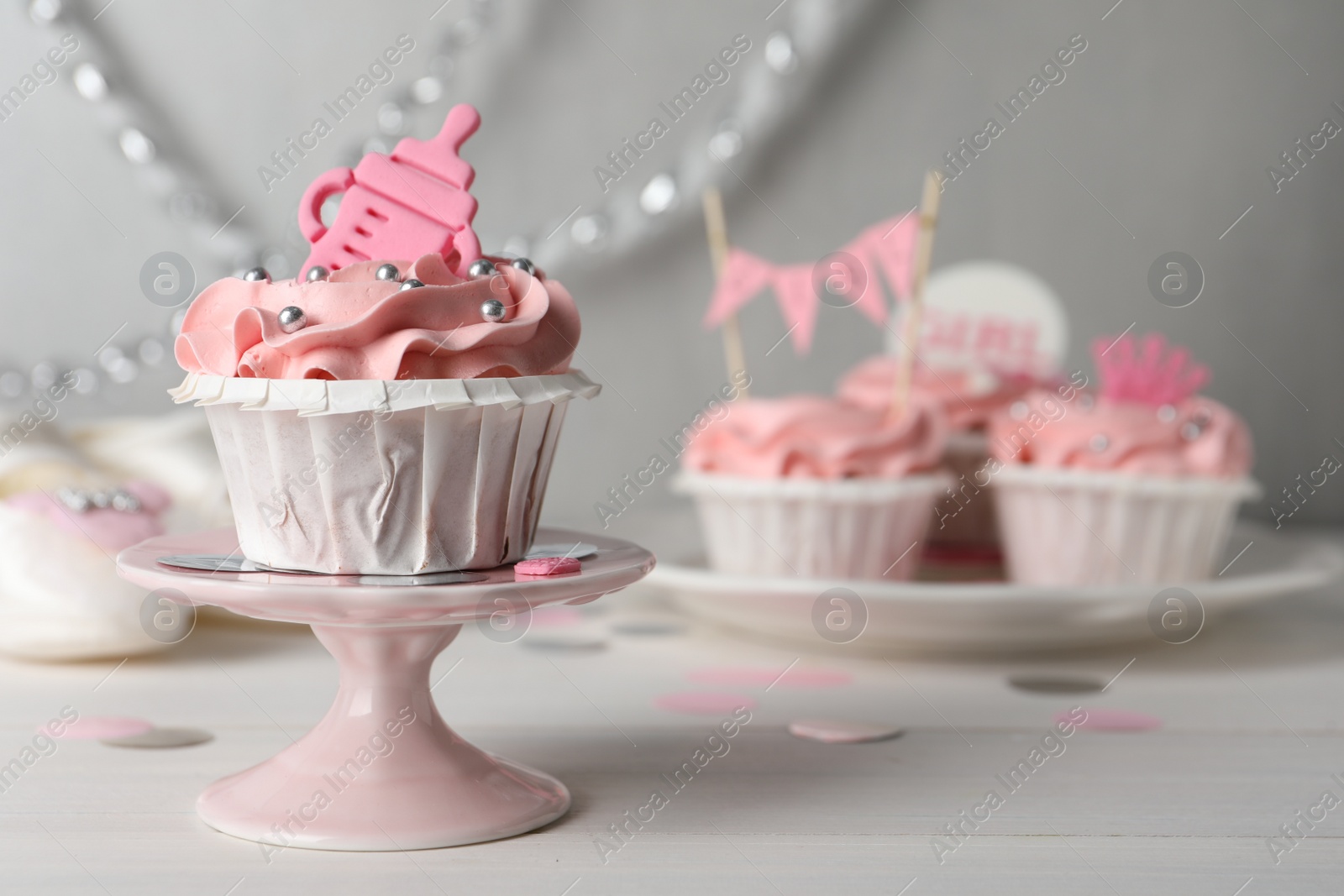 Photo of Delicious cupcake with pink cream and topper on white wooden table, space for text. Baby shower party