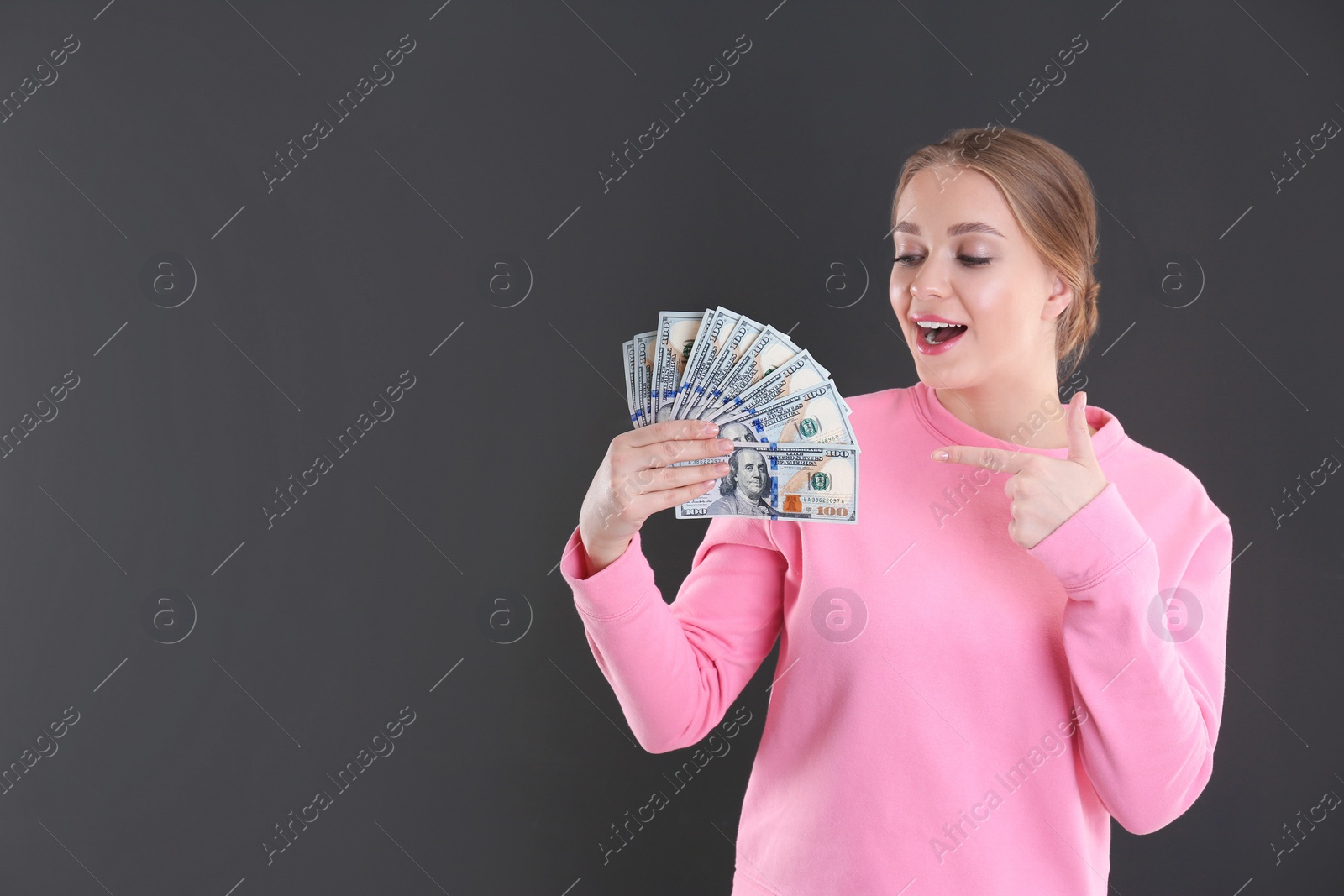 Photo of Portrait of emotional young woman with money on grey background. Space for text