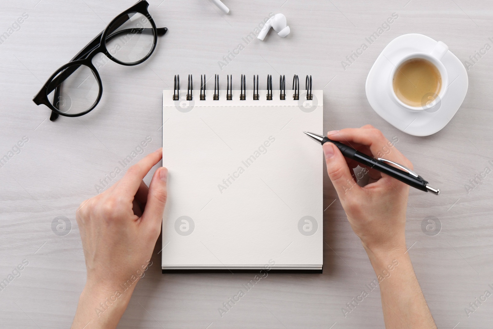 Photo of Woman with notebook and pen at white wooden table, top view. Space for text