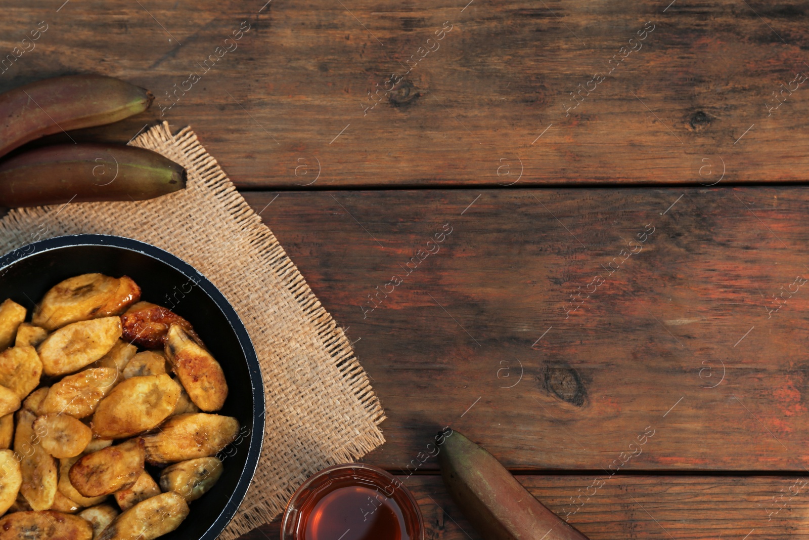 Photo of Flat lay composition with deep fried banana slices on wooden table. Space for text