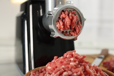 Photo of Electric meat grinder with minced beef on blurred background, closeup