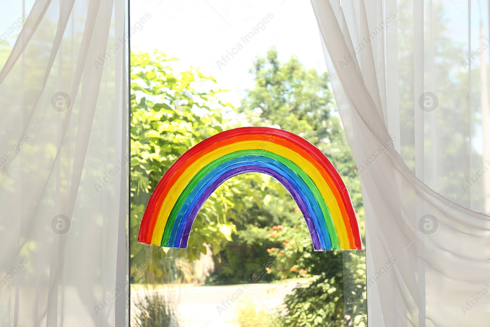 Photo of Painting of rainbow on window indoors. Stay at home concept