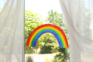 Painting of rainbow on window indoors. Stay at home concept